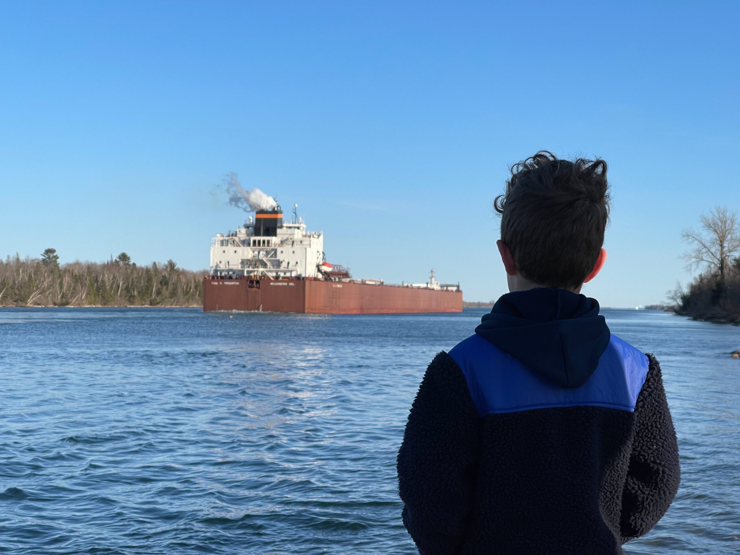 child observing freighter in lake superior